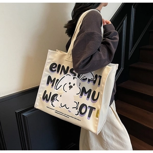 Detail view of cream canvas tote bag with cute dog print and letters in a lifestyle setting