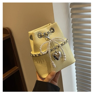 Detail of yellow lychee leather bucket bag with silver chain and pearl bow charm