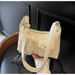 Detail of cream-white utility shoulder bag featuring glossy faux leather and pocket zippers