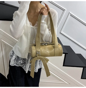 Detail of a khaki Boston bag with oversized bow and wide strap on a model