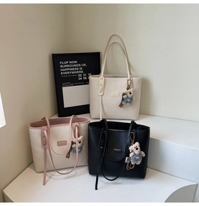Three elegant tote bags in beige, pink, and black featuring plush bear charms and pebbled leather