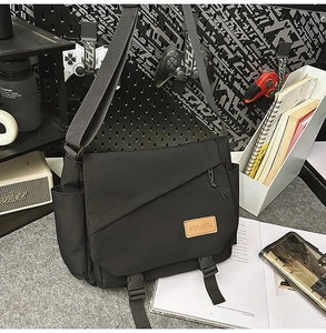 Detail of black tactical messenger bag featuring plastic buckles and waterproof fabric texture