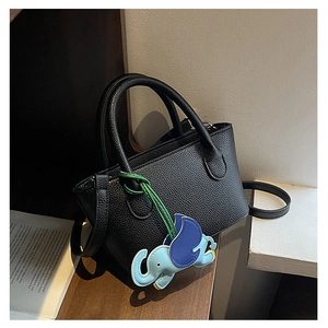 Detail of black lychee grain leather tote bag featuring a cute blue elephant charm accessory
