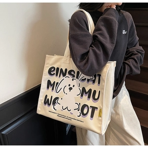 Close-up of a white canvas tote bag with cartoon dog print and purple lettering