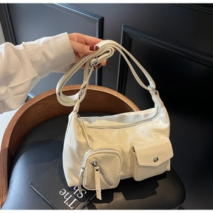 Detail of off-white hobo bag showing front zipper pocket, flap button and textured faux leather