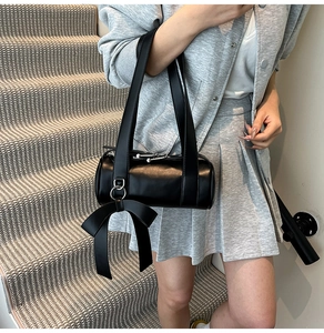 Detail of black Boston bag featuring a large decorative bow and matte leather finish