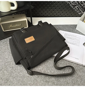 Detail of black nylon messenger bag featuring adjustable strap and buckle closure