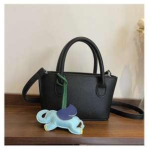 Close-up of black lychee grain bucket bag with a cute light blue elephant leather charm