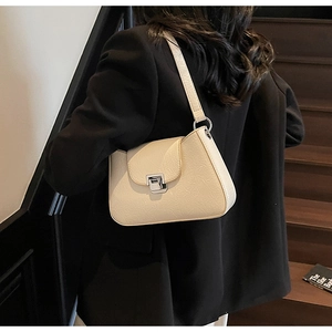 Close-up of cream underarm bag with pleated leather texture and silver metal twist lock