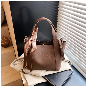 Detail of brown lychee grain leather tote bag with logo and floral scarf accessory