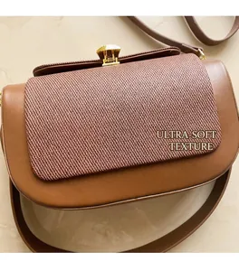 Detail of contrast stitching and woven texture on brown leather crossbody saddle bag