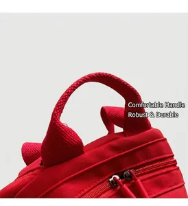 Close-up of red canvas handbag featuring reinforced webbed handles and dual metal zippers