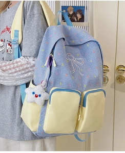 Detail of color-block backpack with yellow zip pockets and star plush charm accessory