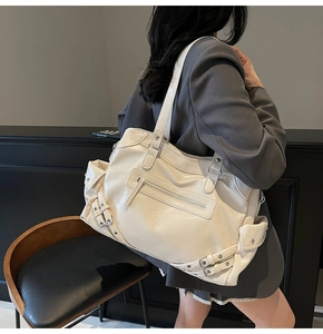 Detail of cream white faux leather tote bag with silver rivets and vintage biker buckles