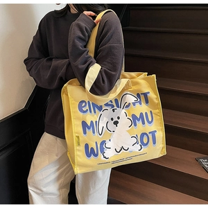 Detail of yellow canvas tote bag featuring cute cartoon puppy and blue art lettering