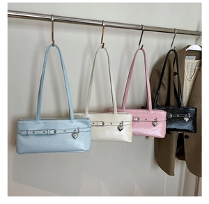 Detail view of four glossy underarm bags in pastel colors with heart-shaped metal pendants