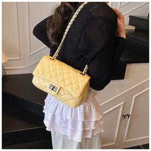 Detailed view of lemon yellow quilted leather handbag with gold chain strap on steps