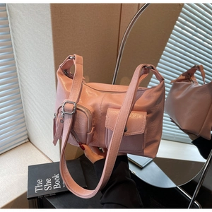 Detail of pink crinkled faux leather shoulder bag featuring silver zippers and cargo pockets