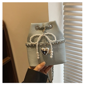 Detail of baby blue bucket bag with pearl bow and silver heart pendant on lychee leather