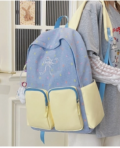 Detail of color-block backpack with blue plaid pattern and cute plush charm pendant