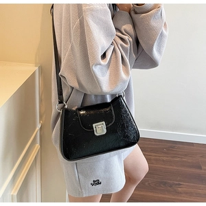 Détail du sac bandoulière en similicuir noir craquelé avec boucle carrée en métal argenté