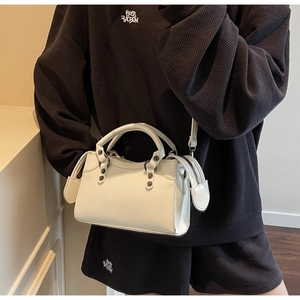 Detail der cremefarbenen Ledertasche mit Vintage-Metallnieten und verstellbarem Riemen