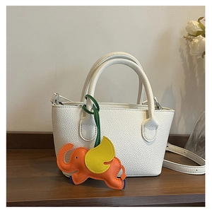 Close-up of white lychee pattern tote bag featuring a cute orange elephant charm accessory
