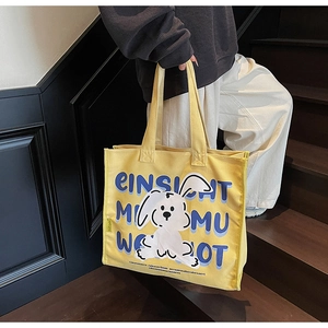 Detail of yellow canvas tote bag featuring white cartoon rabbit and blue letter printing