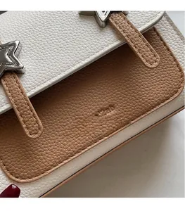 Close-up of pebble leather texture and silver star buckle on a bicolor crossbody bag