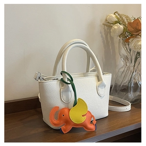 Close-up of white lychee pattern bucket bag with a colorful orange elephant charm detail