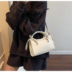 Detailansicht der Vintage-Faltenstruktur und Metallnieten-Akzente auf der weißen Handtasche