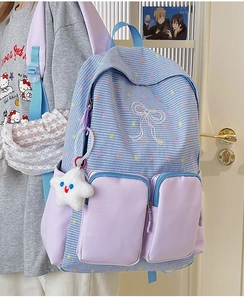 Detailed view of blue plaid school backpack with purple pockets and star charm accessory