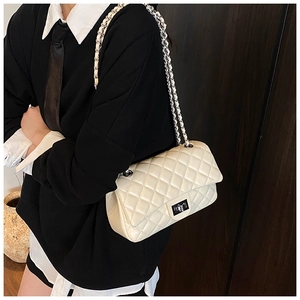 Detail view of cream quilted crossbody bag with metal chain strap on model