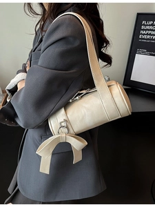 Creamy white cylindrical Boston bag with leather bow charm and wide shoulder strap