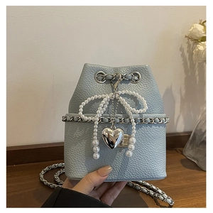 Detail of light blue lychee pattern bucket bag with pearl bow and silver heart pendant