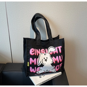 Detail of black canvas tote bag featuring a cute white rabbit illustration and pink lettering