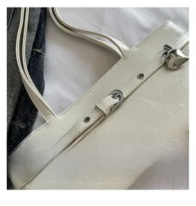 Close-up of beige textured leather shoulder bag with silver heart lock and metal buckle