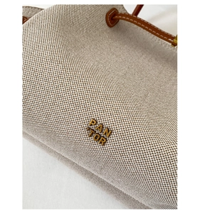 Close-up of canvas tote bag showing heavy fabric texture and brown leather logo detail