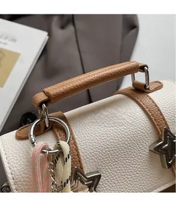 Detail of white lychee leather handbag with star metal decor and woven charm