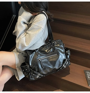 Detail of black PU leather tote with metal zippers and adjustable buckles on stairs