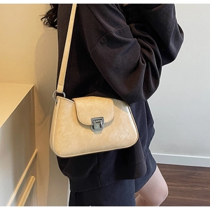 Close-up of beige wrinkled leather shoulder bag with a silver metal buckle lock