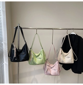 Tote bags in black, green, pink, and beige colors hanging on a rack for display