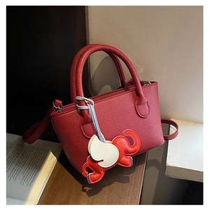 Detail of red lychee grain bucket bag featuring a cute winged elephant charm accessory