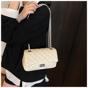 Close-up of cream quilted crossbody bag with silver chain strap and metal turn-lock