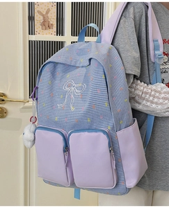 Detail of blue plaid backpack with purple pockets and soft white plush ball accessory