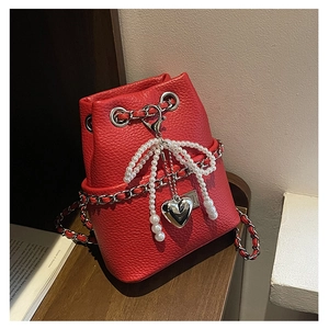 Detailed macro of red litchi grain bucket bag with pearl bow and silver heart charm