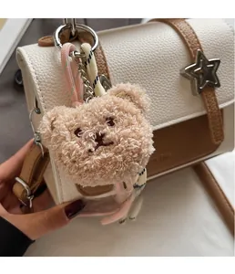 Detail of curly plush bear pendant with braided rope on a brown leather handbag