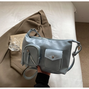 Detail view of a light blue vintage faux leather bag with pockets on a white bed