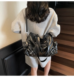 Detailed back view of a black glossy tote bag with metal buckles on a fashion model