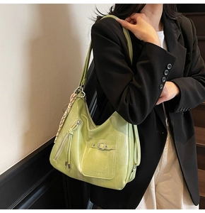 Detailed view of a light green shoulder bag with silk scarf charm and metal zipper decor